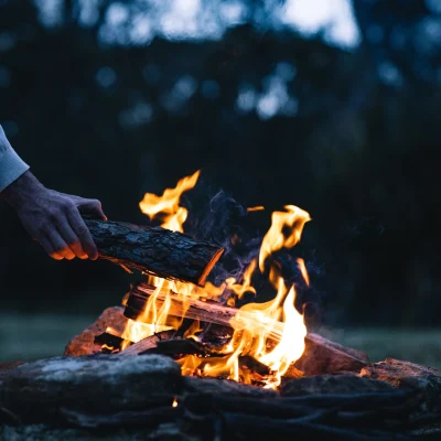 man-putting-log-bonfire-evening